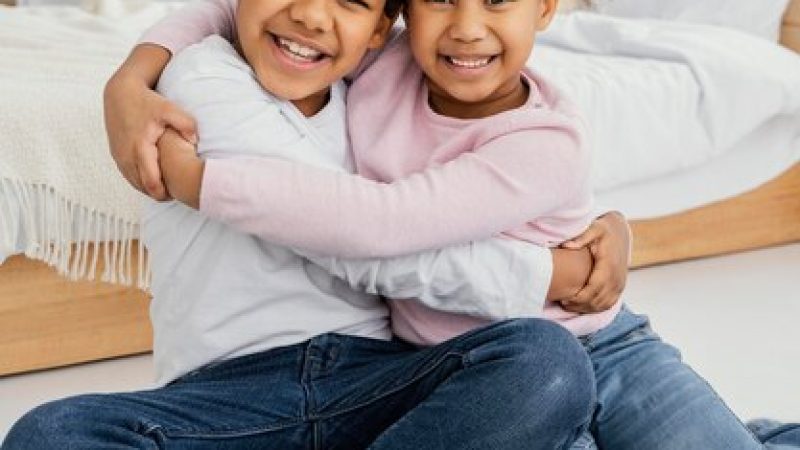 front-view-two-smiley-siblings-embracing-each-other-home_23-2148890950